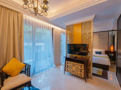 a bedroom with a bed and a tv in a room at Jambuluwuk Oceano Seminyak Hotel in Seminyak
