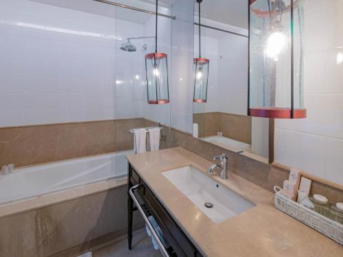 a bathroom with a sink and a large mirror at Jambuluwuk Oceano Seminyak Hotel in Seminyak