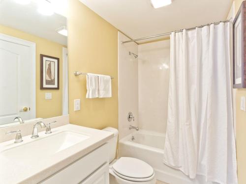 a white bathroom with a sink and a toilet and a tub at Gull Reef 635 in Tybee Island