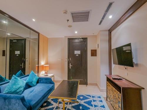 a living room with a blue couch and a table at Jambuluwuk Oceano Seminyak Hotel in Seminyak