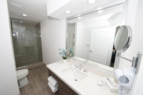 a white bathroom with a sink and a mirror at Las Vegas Serene Hotel in Las Vegas