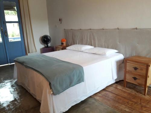 Un dormitorio con una gran cama blanca y una mesa en Pousada Santa Maria, en Tiradentes