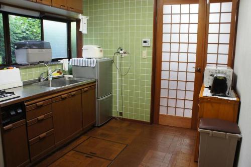 a kitchen with green tiled walls and a sink at EK House Hakone Shushinso 箱根修身荘 in Onsensō