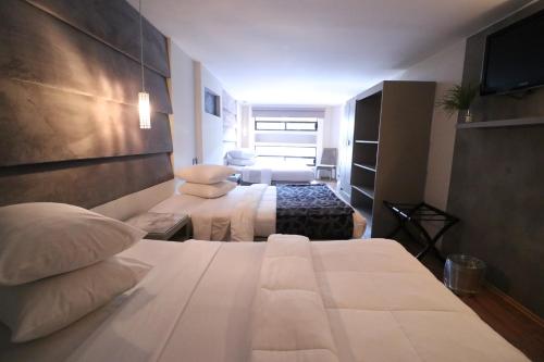 a hotel room with two beds and a television at Hotel Posada Tulancingo in Tulancingo