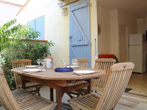 - une table et des chaises en bois avec des verres à vin dans l'établissement Maison cosy avec terrasse, clim et parking, à 250m de la plage - FR-1-229C-662, à Port-la-Nouvelle