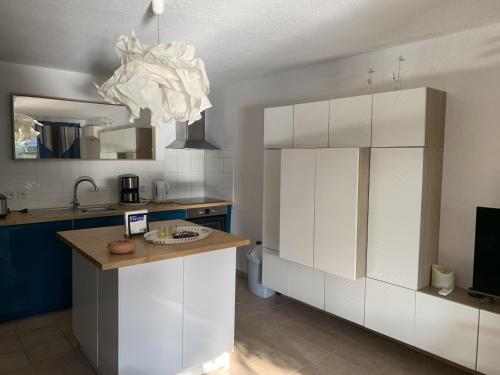 une cuisine avec des armoires blanches et un lustre dans l'établissement Appartement climatisé à Collioure : Terrasse, Wi-Fi, Piscine chauffée, Parking privé. - FR-1-309-143, à Collioure
