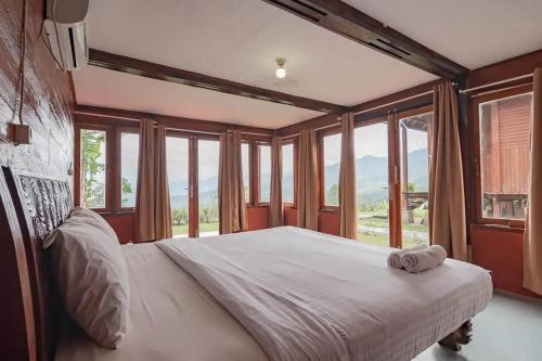 um quarto com uma cama grande e janelas de vidro em Kanaka Residence Mitra RedDoorz em Bandungan