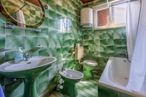 a green tiled bathroom with a sink and a toilet at Apartment Kreso in Punat