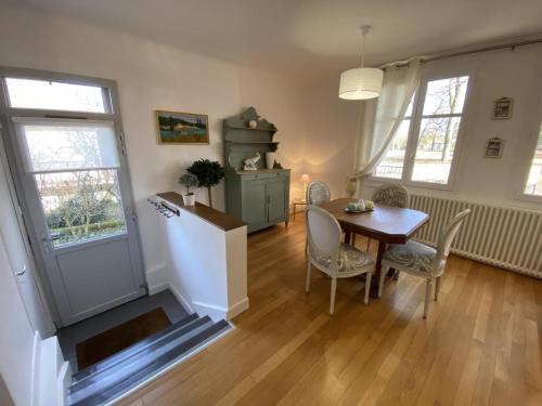 une salle à manger avec une table, des chaises et une porte dans l'établissement Charmante maison avec jardin en face du parc, proche commerces et attractions touristiques - FR-1-489-333, à Moulins