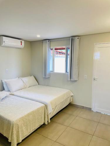 a bedroom with two beds and a window at Anexo Marques in Paraty