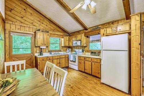 a kitchen with wooden cabinets and a white refrigerator at Peak-a-Blue Cabin - Watch Movies from Hot Tub, Mountain View, Bigfoot Bunker Game Room, Fire Pit, Oversized Deck, Screened-in Porch in Mineral Bluff