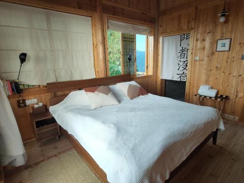 a bedroom with a large white bed with a window at 昭希舍 Banji Arbre House, a traditional lodge home on rice terrace in Liping
