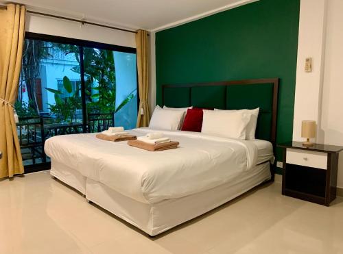 a bedroom with a large white bed with a green wall at 4U Resort Samui in Lamai