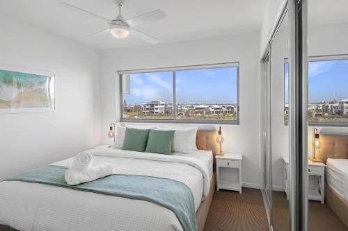 a white bedroom with a large bed and a window at Pool, 100m to Hosp, 3 TVs, 3 Beds - Lakefront Aquarius Apartment in Kawana Waters