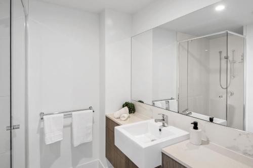 Baño blanco con lavabo y espejo en Pool, 100m to Hosp, 3 TVs, 3 Beds - Lakefront Aquarius Apartment en Kawana Waters