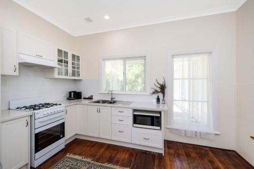 a white kitchen with a stove and a sink at Busselton River Cottage with WiFi in Busselton