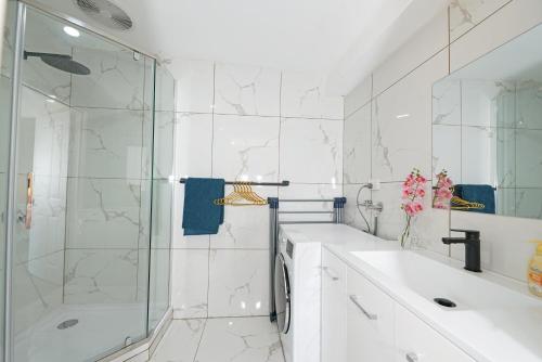 a white bathroom with a shower and a sink at Beachside Compact Backyard Cabin near Mentone in Parkdale