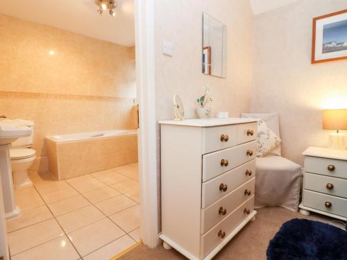 a bathroom with a white dresser and a sink at Rosemary Cottage in Bourton on the Water