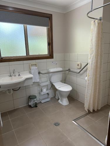 a bathroom with a toilet and a sink and a window at Chiltern Lodge Country Retreat in Old Bar