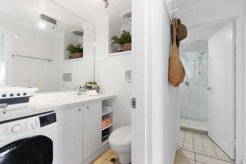 a white bathroom with a toilet and a sink and a shower at Portofino 1 in Noosa Heads