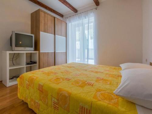 a bedroom with a yellow bed and a television at Apartments Jadranka in Dramalj