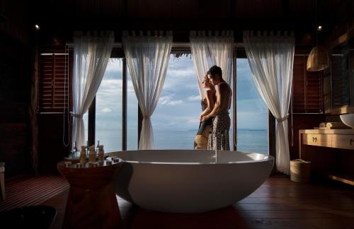 a man and woman standing in a bath tub in a bathroom at Papua Paradise Eco Resort in Pulau Birie