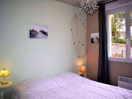 een slaapkamer met een wit bed en een raam bij Maison Perros-Guirec, 4 pièces, 7 personnes - FR-1-368-57 in Perros-Guirec