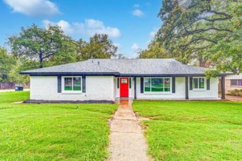 ein weißes Haus mit einer roten Tür im Hof in der Unterkunft Spacious/Cozy home in Fort Worth in Fort Worth