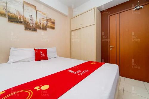 a bedroom with a bed with a red blanket on it at RedLiving Apartemen Green Lake View Ciputat - Pelangi Rooms 1 Tower E in Pondokcabe Hilir