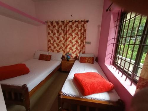 two beds in a room with two windows at Nakshatra Homestay in Madikeri