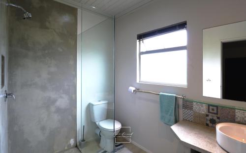 a bathroom with a shower and a toilet and a sink at Lovely brand new flat near restaurants and beach with solar - free wifi and DSTV in Cape St Francis