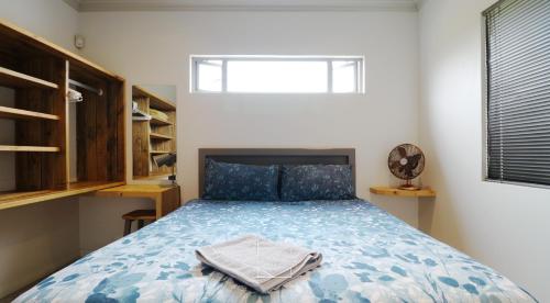 1 dormitorio con 1 cama con edredón azul y ventana en Lovely brand new flat near restaurants and beach with solar - free wifi and DSTV, en Cape St. Francis