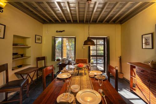 a dining room with a long wooden table and chairs at StayVista at Tea House 2BR with fragrant tea gardens in Dharamshala in Dharamshala