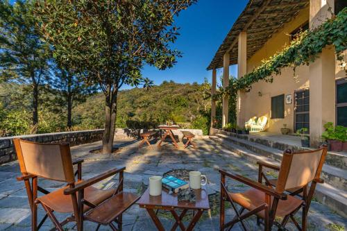 a patio with two chairs and a table at StayVista at Tea House 2BR with fragrant tea gardens in Dharamshala in Dharamshala
