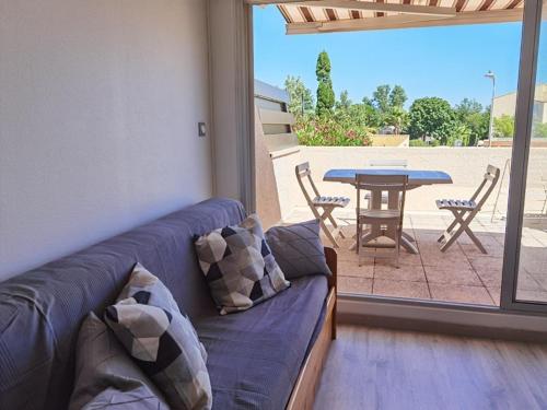 un salon avec un canapé bleu et une table dans l'établissement Appartement Climatisé 2 Pièces avec Terrasse et Parking - Classé 2 Étoiles - FR-1-326-690, à Marseillan