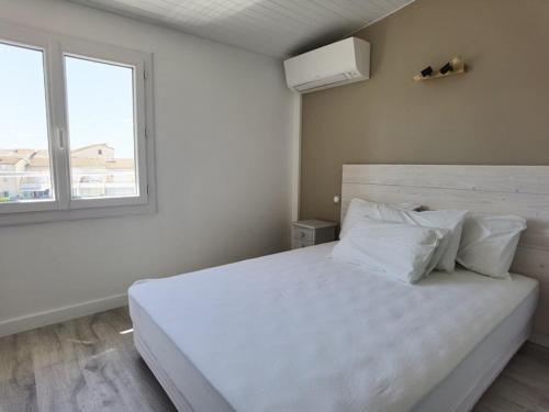 une chambre avec un grand lit blanc avec une fenêtre dans l'établissement Appartement Climatisé 2 Pièces avec Terrasse et Parking - Classé 2 Étoiles - FR-1-326-690, à Marseillan