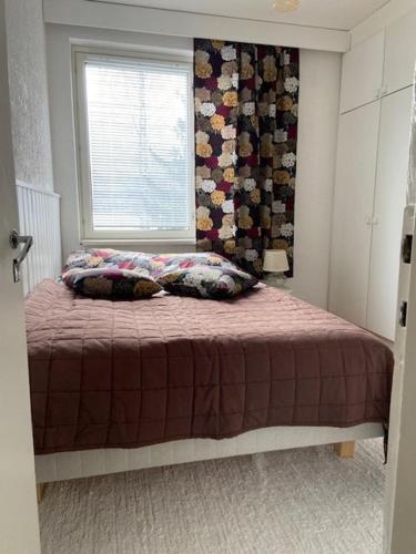 a bedroom with a bed with a window and a blanket at Huoneisto Jalkarannassa in Lahti
