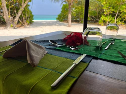 a table with a green table cloth and a glass at The Barefoot Eco Hotel in Hanimaadhoo