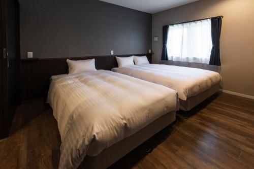 2 Betten nebeneinander in einem Zimmer in der Unterkunft Ahman Inn Island Yagaji in Nago