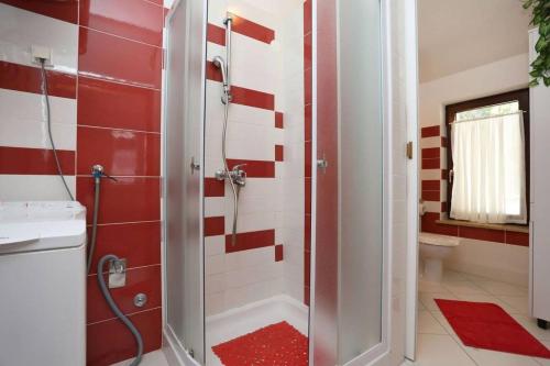 uma casa de banho com um chuveiro com azulejos vermelhos e brancos em Apartments Nada em Rabac