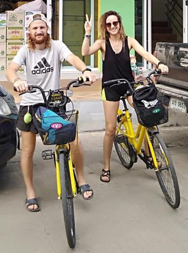 two people riding bikes down a street with at Baansrisuthum in Don Sak