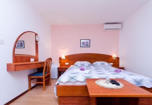 a bedroom with a bed and a desk and a table at Rooms Mladen P in Banjol