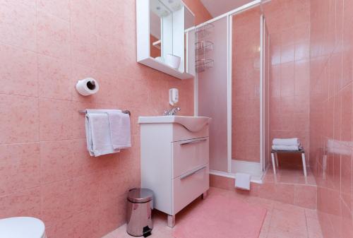un bagno rosa con lavandino e doccia di Rooms Mladen P a Banjol