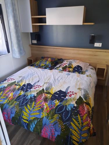 um quarto com uma cama com um edredão colorido em jpp marie ange proprietaire em Saint-Julien-en-Born