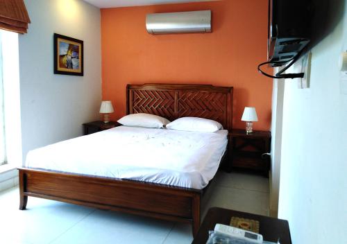 a bedroom with a bed with white sheets and pillows at Morgah Resort - Guest Rooms in Rawalpindi