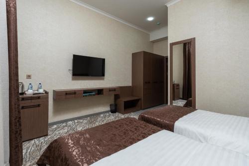 a hotel room with two beds and a flat screen tv at ABIS Palace Hotel in Tashkent