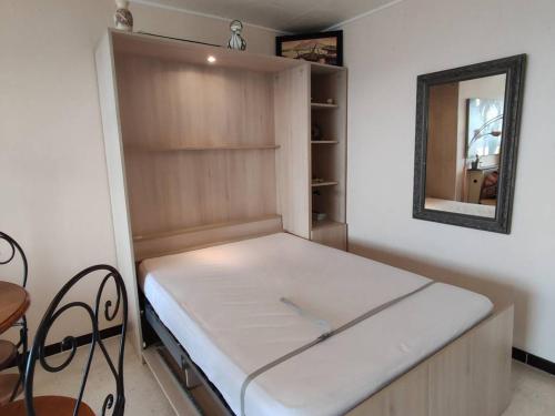 - un petit lit dans une chambre avec un miroir dans l'établissement Studio à Balaruc-les-Bains avec climatisation et animaux acceptés - FR-1-571-53, à Balaruc-les-Bains
