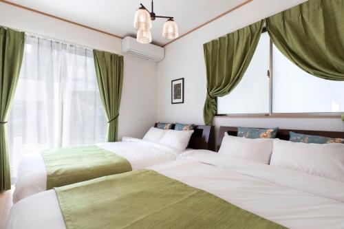 two beds in a room with green curtains at Y's沖縄リゾートベースNo.1 in Onna