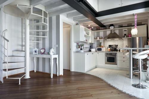 una cocina con armarios blancos y una escalera de caracol en Your little Loft, en Villafranca di Verona