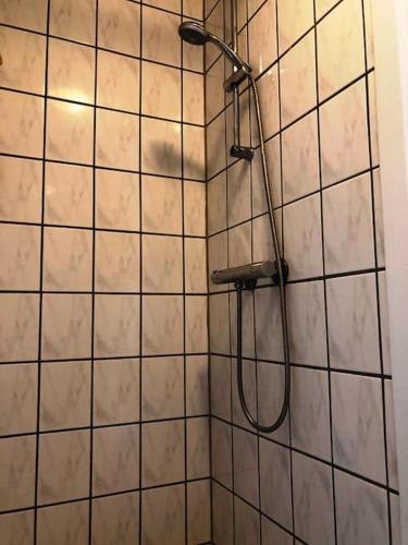 prysznic z głowicą prysznicową na ścianie wyłożonej kafelkami w obiekcie Lejlighed i midtby - tæt på alt w mieście Viborg